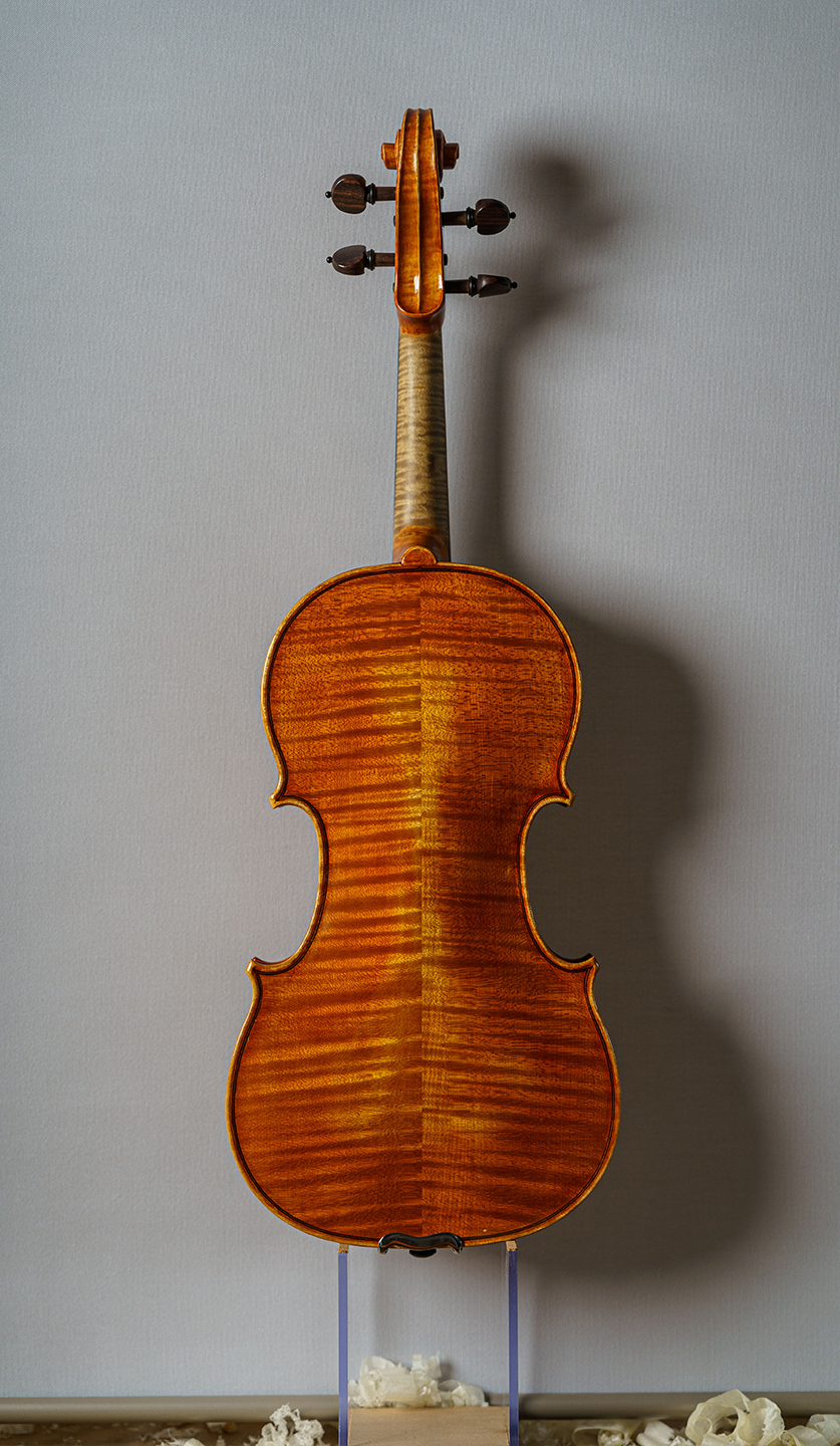 vista trasera de uno de los violines color chocolate de Stefan Marinescu sobre peana